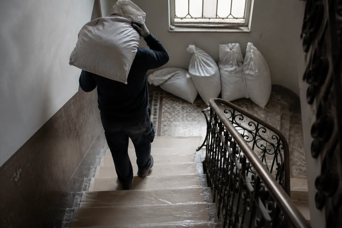 Operario bajando un saco de escombro por la escalera protegida de una finca sin ascensor en Valencia