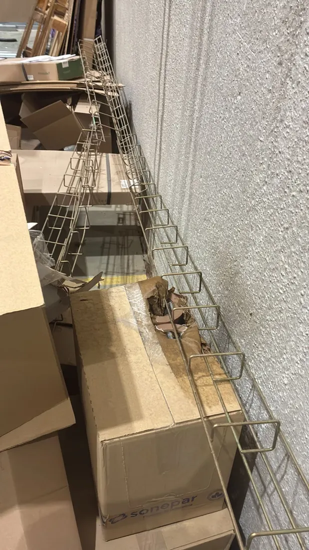 Bandejas metálicas de rejilla para cables junto a cajas de cartón en una nave