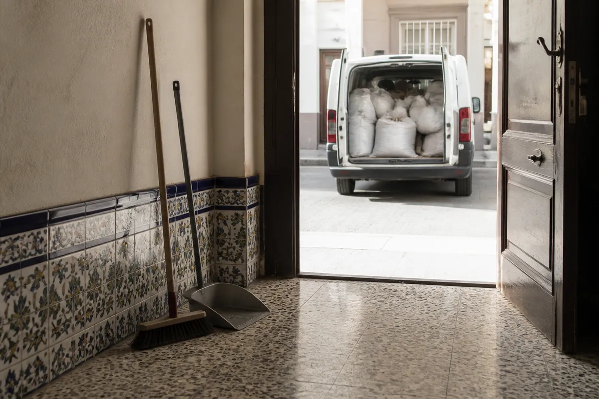 Portal de una finca de Valencia barrido después de la retirada de escombros, con la furgoneta cargada en la puerta