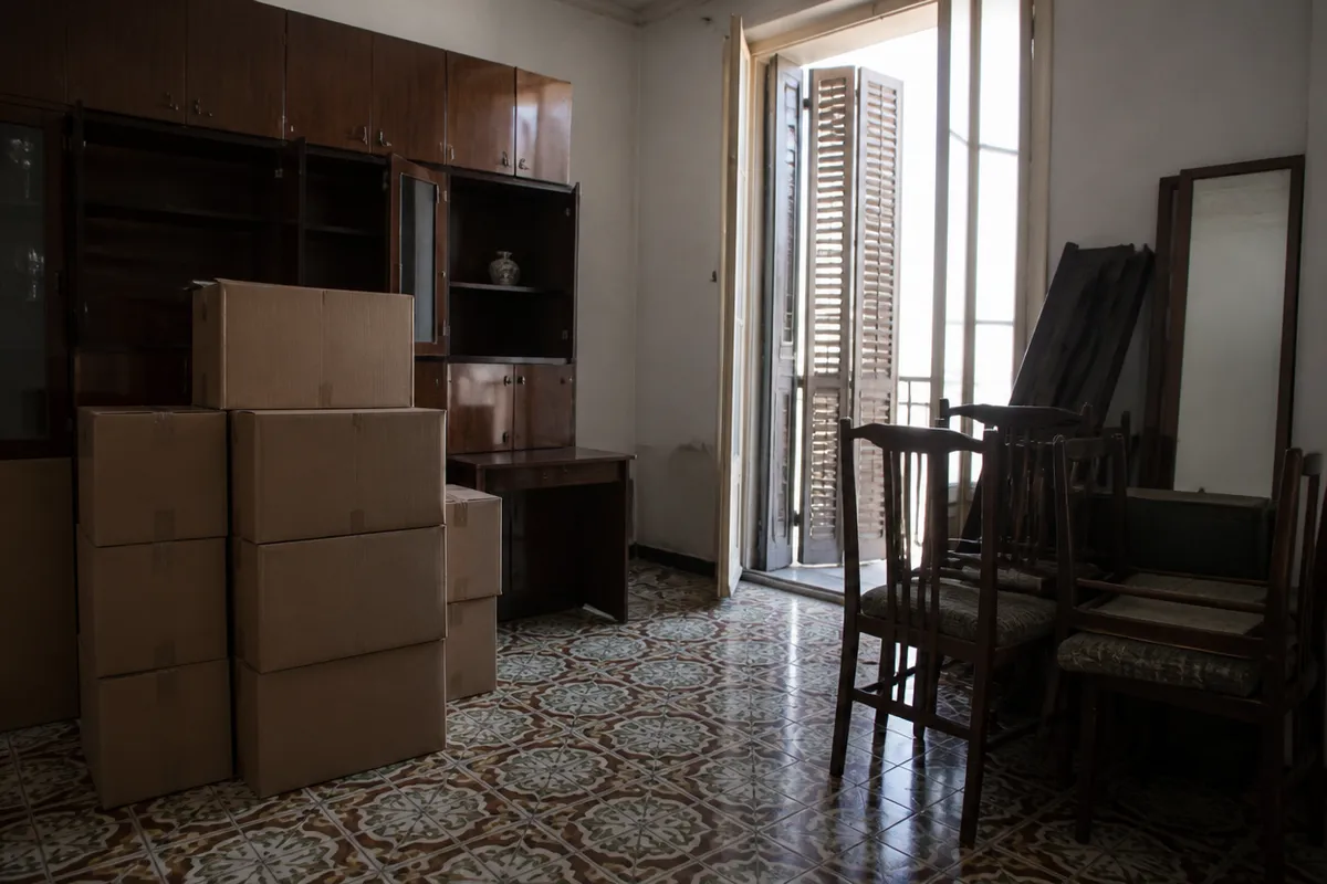 Salón de un piso antiguo de Valencia a medio vaciar, con cajas y muebles por retirar
